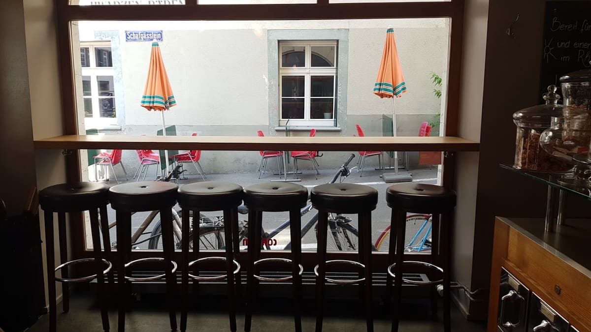 Hohe Tische und Barhocker im Consum, durch das offene Fenster die Terrasse an der Rheingasse