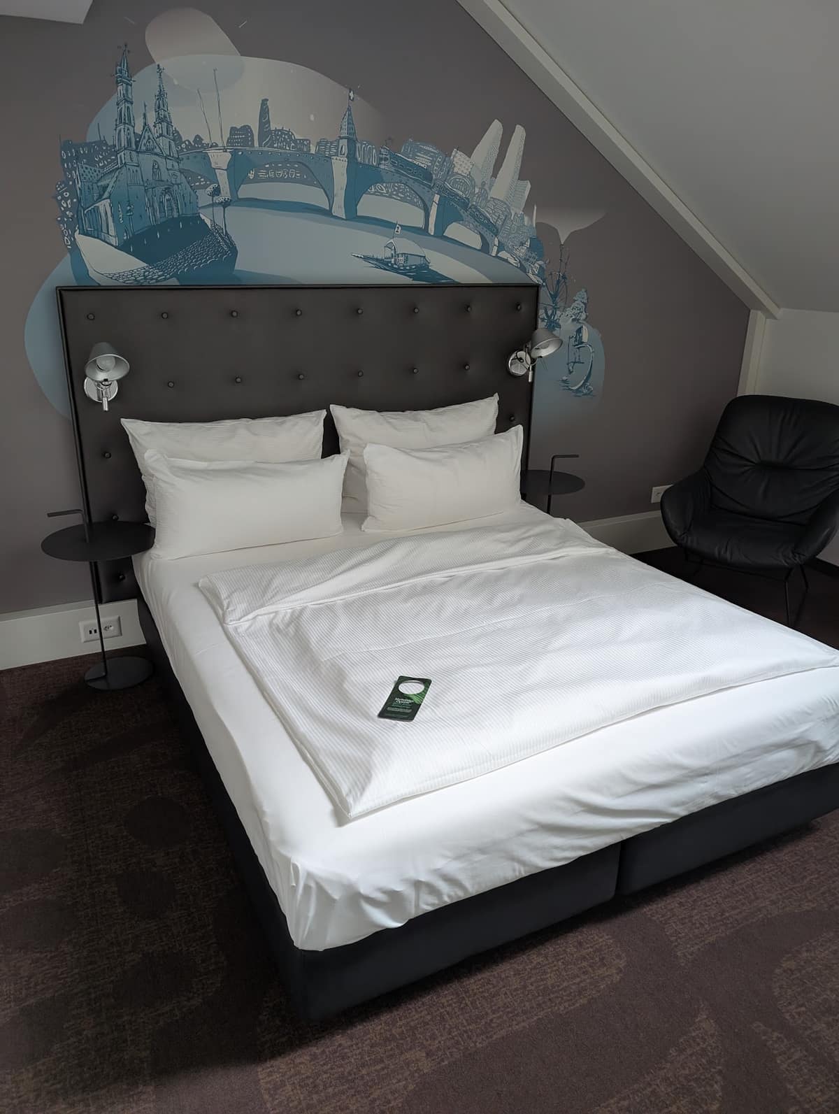 A double room at Motel One Basel with a dark headboard and white bedding
