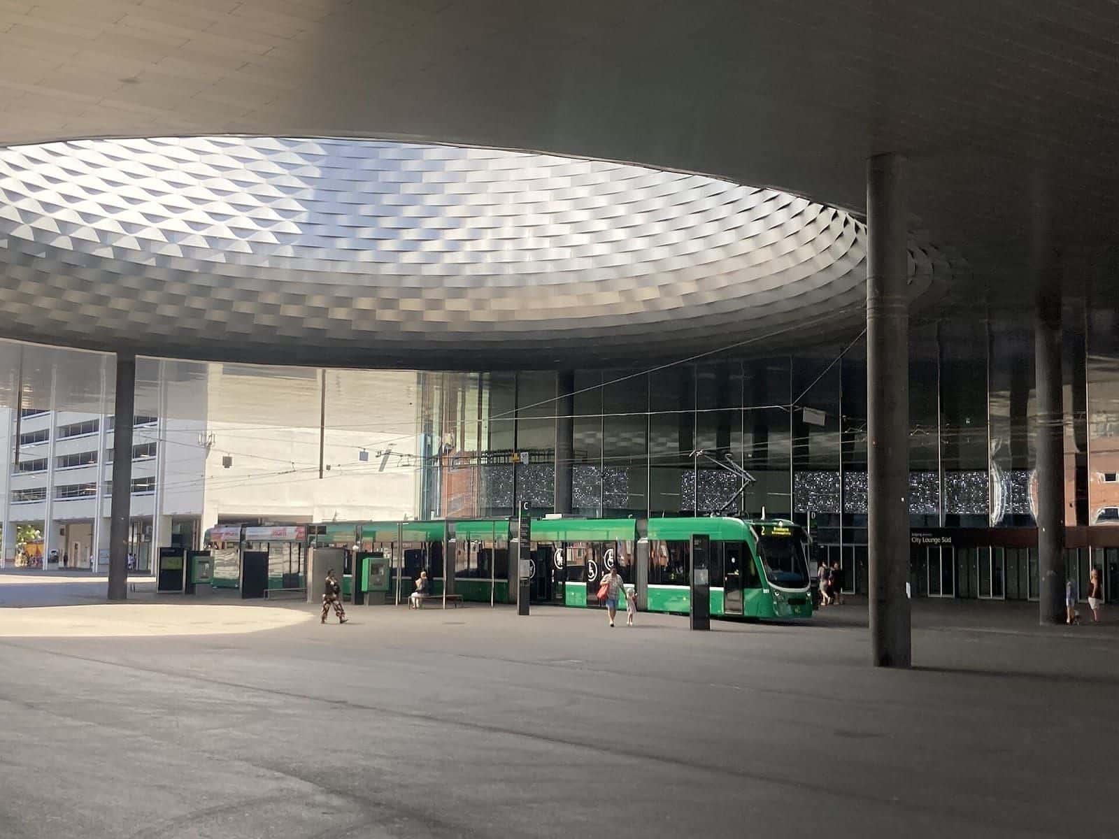 Ein grünes Tram der Linie 2 an der Haltestelle Messeplatz unter dem runden Ausschnitt im Dach der Halle 1
