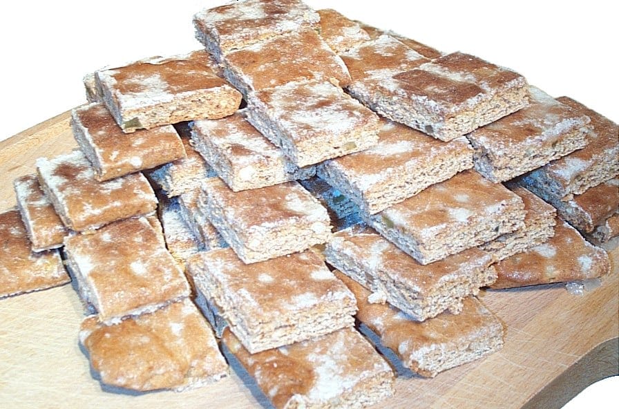 Basler Läckerli in Rechtecke geschnitten, mit weisser Zuckerglasur, auf einem Holzbrett gestapelt