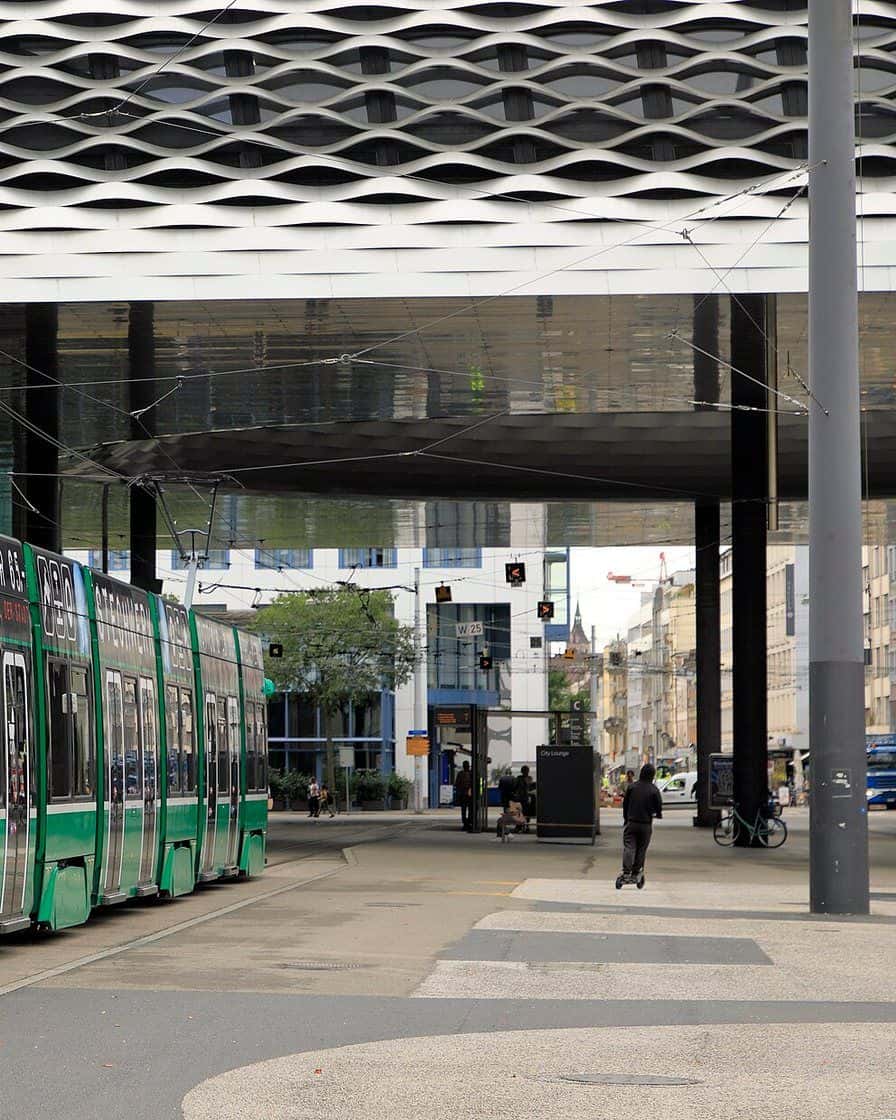 Messeplatz in Basel under the roof of Hall 1 with its round opening, a green tram at the stop