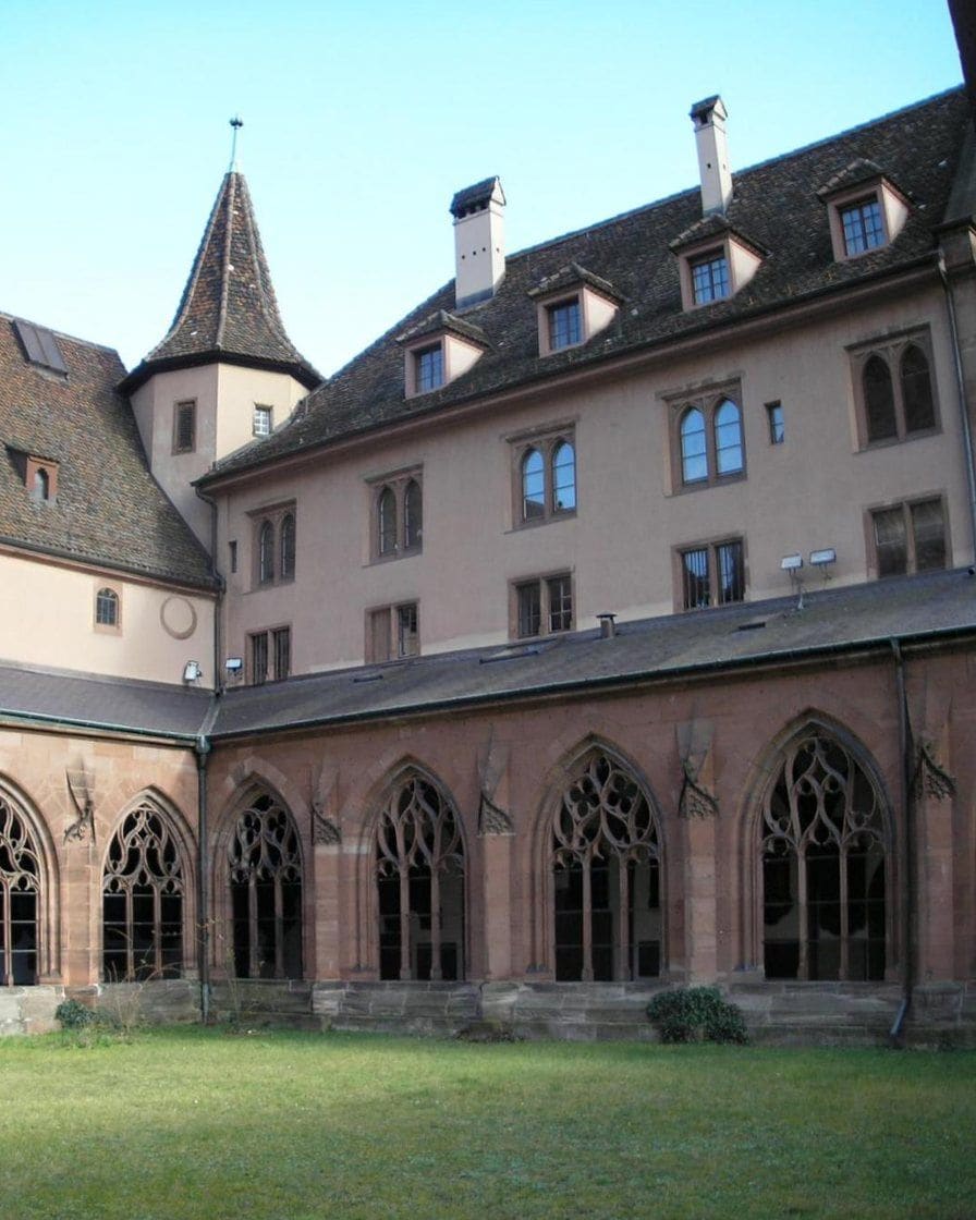 Ein Hof des Kreuzgangs am Basler Münster mit gotischen Spitzbogenfenstern aus rotem Sandstein
