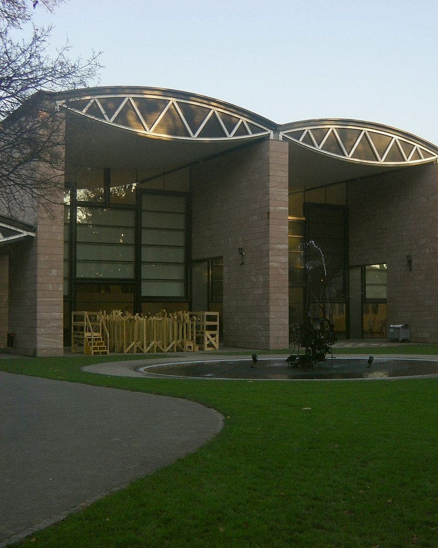 Das Museum Tinguely von Mario Botta im Solitude-Park in Basel, mit seinem geschwungenen Glasdach und dem Rasen davor