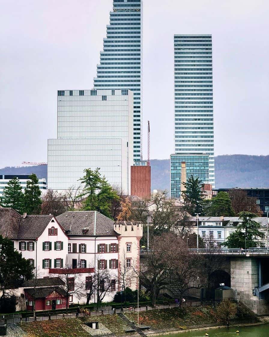 Les deux tours blanches de Roche à Bâle, avec leurs silhouettes en gradins, vues depuis la rive du Rhin par-dessus les toits