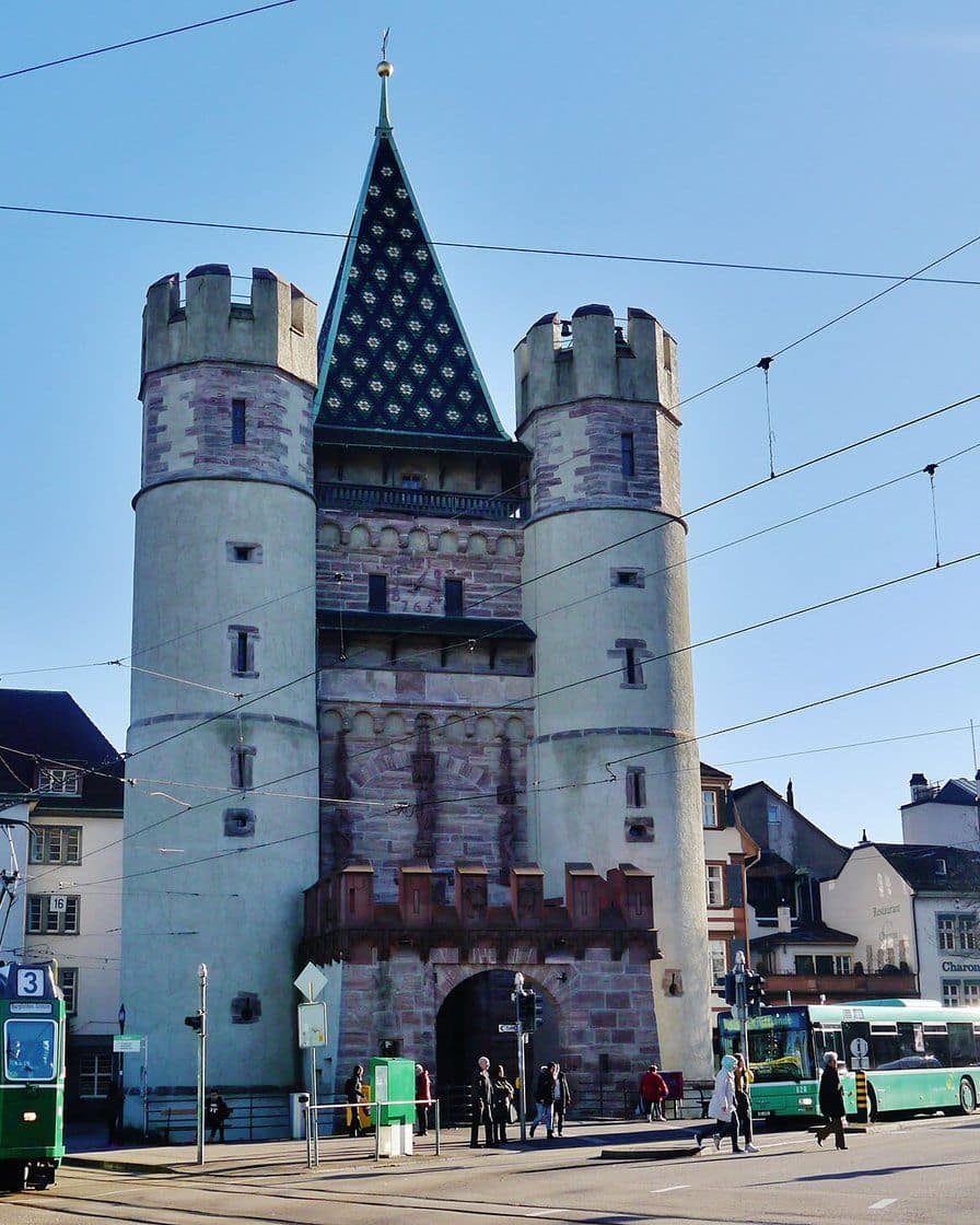 Das Spalentor in Basel, ein mittelalterliches Stadttor mit buntem Ziegeldach und zwei Rundtürmen, an einem sonnigen Tag