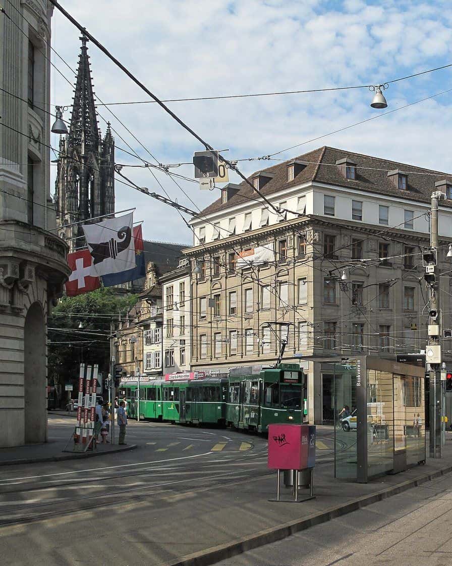 A green tram in front of old commercial buildings on St. Alban-Graben in Basel