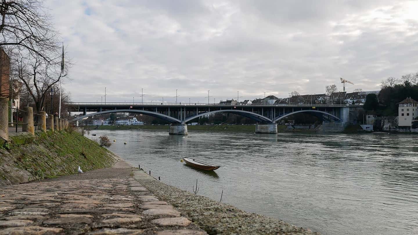 Die Wettsteinbrücke über den Rhein in Basel, vom flachen Ufer aus gesehen, ein kleines Boot im Wasser